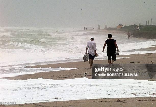 Two men walk along the Miami Beach shoreline 25 September between storm bands from Hurricane Georges. The eye of Georges is passing over Key West,...