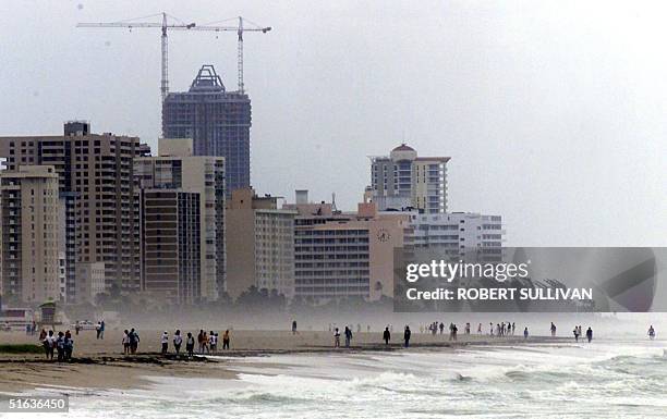 People walk along Miami Beach between storm bands of Hurricane Georges 25 September. Georges' eye is passing over Key West, FL. AFP PHOTO/Robert...