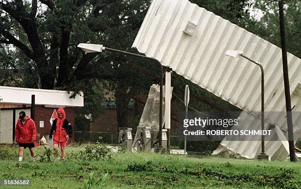 Two residents of Gulfport, Mississippi, walk away from a partially damaged gas station following the high winds of Hurricane Georges 28 September on...