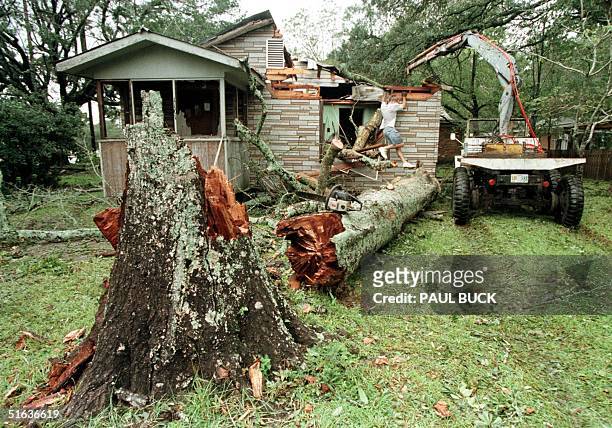 Tim Pauls helps the owner of a house in Ocean Springs, Mississippi bring a tree off the roof of his house 29 September after hurricane winds brought...