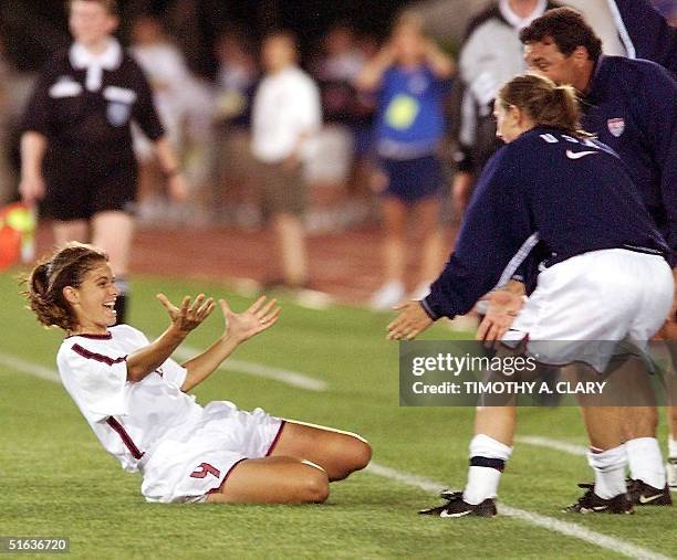 Soccer team forward Mia Hamm slides across the grass into her teammates after scoring her 2nd goal of the night during the 2nd half of the gold medal...