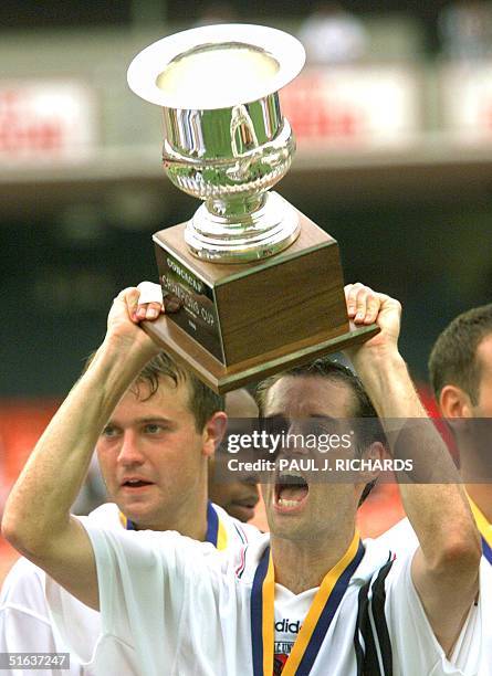United midfielder John Harkes holds the 1998 CONCACAF Champions Cup trophy after DC United defeated CD Toluca 1-0 16 August in the final of the...