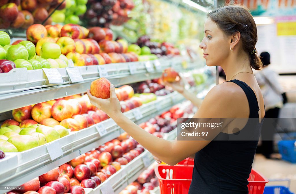 Mulher compra maçãs no supermercado