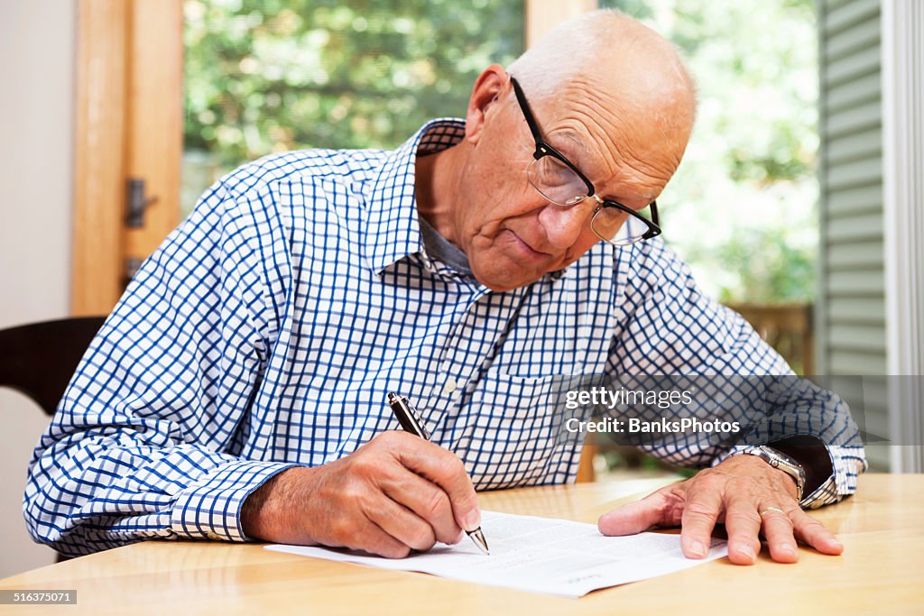Alter Mann ausfüllen Papierkram, die Unterzeichnung des Dokuments