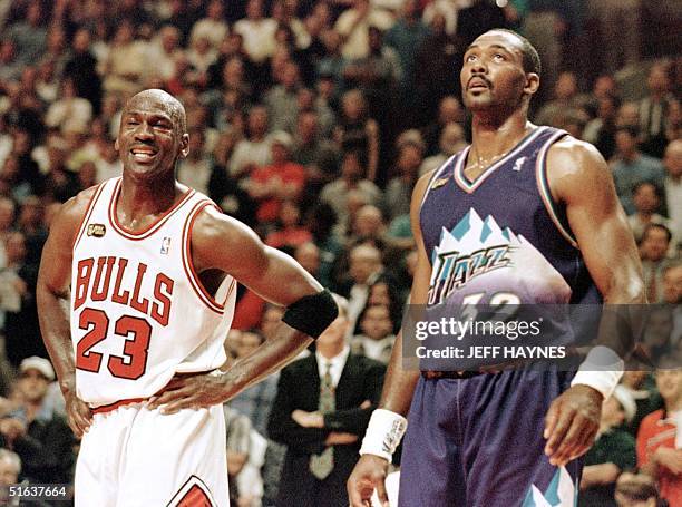 Michael Jordan of the Chicago Bulls smiles while standing next to Karl Malone of the Utah Jazz 07 June in the first half of game three of the NBA...