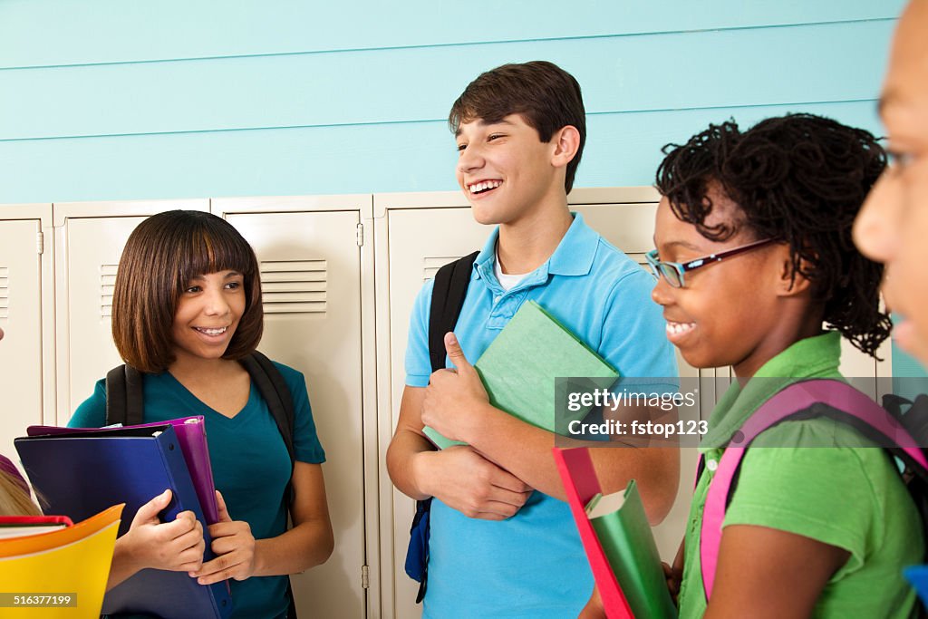 Grupo diverso de estudiantes adolescente hablando en pasillo de la escuela.  Casilleros.