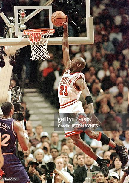 Michael Jordan of the Chicago Bulls flies in for the dunk while Karl Malone of the Utah Jazz watches 10 June during game four of the NBA Finals at...