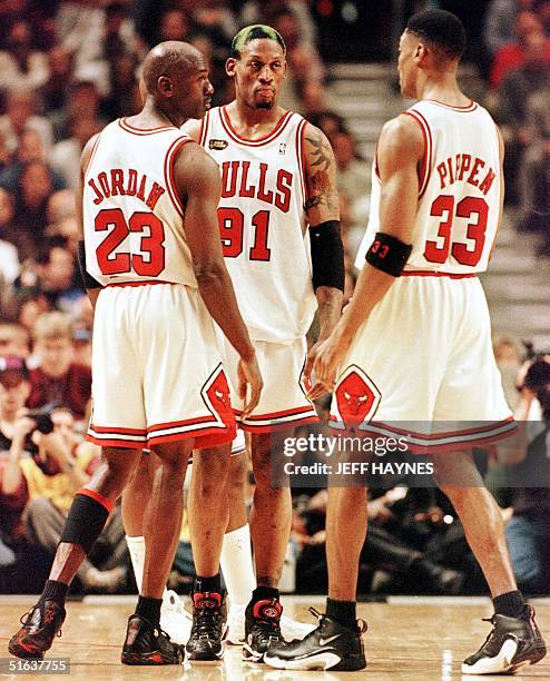 Dennis Rodman of the Chicago Bulls talks to teammates Michael Jordan and Scottie Pippen 10 June during game four of the NBA Finals against the Utah...