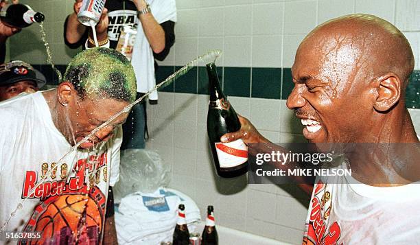 Dennis Rodman of the Chicago Bulls gets beer and champagne poured on his head by teammate Michael Jordan and others 14 June after winning game six of...