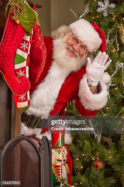 real santa claus hiding behind christmas tree - santa waving stock pictures, royalty-free photos & images