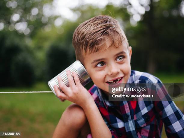 niño travieso música en teléfono de lata en sus manos - tin can phone fotografías e imágenes de stock