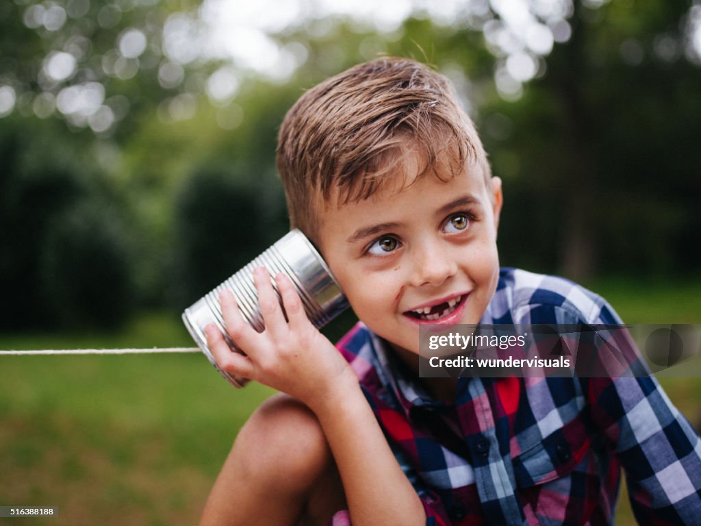 Ragazzo malizioso ascolto di latta telefono in mano