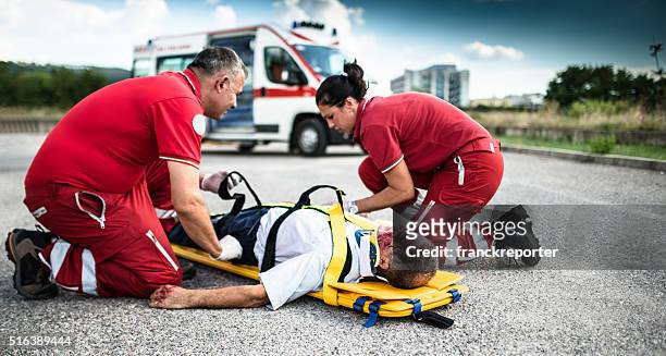 rescue team bei verletzten mann - paramedics stock-fotos und bilder