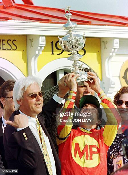 Jockey Kent Desormeaux holds up the Woodlawn Vase along with trainer Bob Baffert in the winner's circle after their horse Real Quiet won the 123rd...