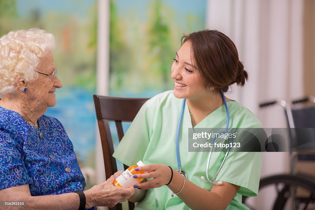 Home healthcare nurse explains prescription medicine to elderly woman.
