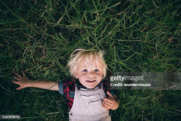 cute blonde child lying on the grass - children nature bildbanksfoton och bilder