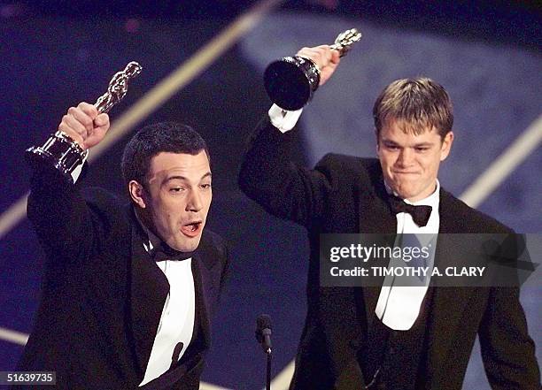 Ben Affleck and Matt Damon hold up their Oscars after winning in the Original Screenplay Category during the 70th Academy Awards at the Shrine...