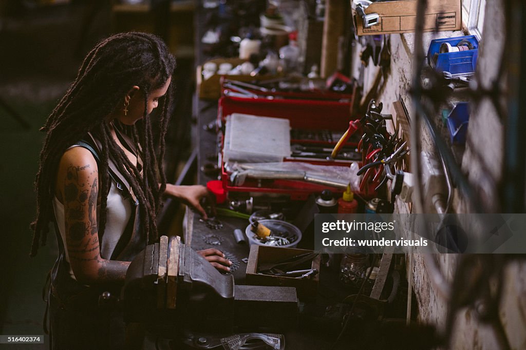 Afro craftswoman assembling bicycle parts at her work bench