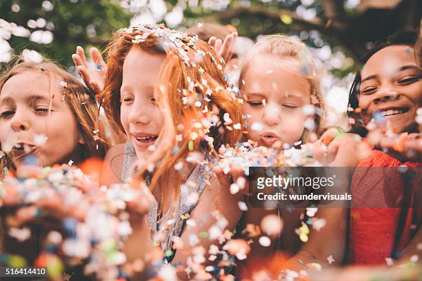 colourful paper confetti being blown at the camera by children - kids party stock pictures, royalty-free photos & images