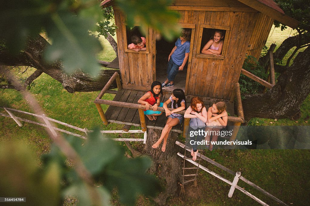 Girls and boys talking and playing in a wooden treehouse