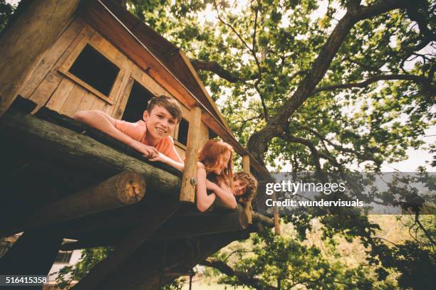 junge lächelnd beim spielen mit freunden in einer hölzernen baumhaus - tree house stock-fotos und bilder