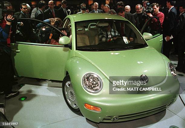 Members of the media surround the new Volkswagen Beetle after its introduction 05 January at the North American International Auto Show in Detroit,...