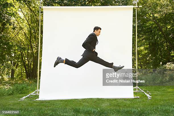 business man on backdrop in nature jumping - spagat stock-fotos und bilder