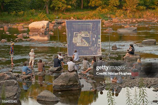 people on river sitting in front of movie screen - new paltz imagens e fotografias de stock