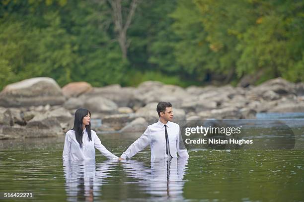 couple holding hands walking in water - 水につかる ストックフォトと画像