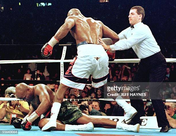 Evander Holyfield is pushed away by referee Mitch Halpern after Holyfield knocked down Michael Moorer for the second time in the eighth round of...