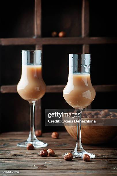 italian liqueur with hazelnut on the wooden table - liqueur - fotografias e filmes do acervo