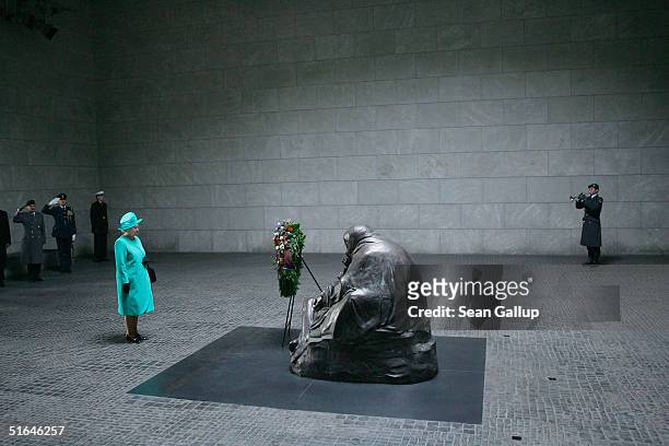 British Queen Elizabeth II stands in respect after laying a wreath at the Neue Wache war memorial while a military trumpeter plays on the first day...