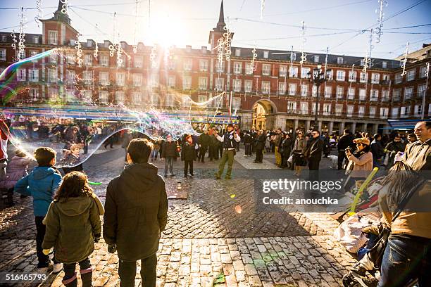 foule visite d'un marché de noël sur la plaza mayor, madrid - statue de philippe iii photos et images de collection