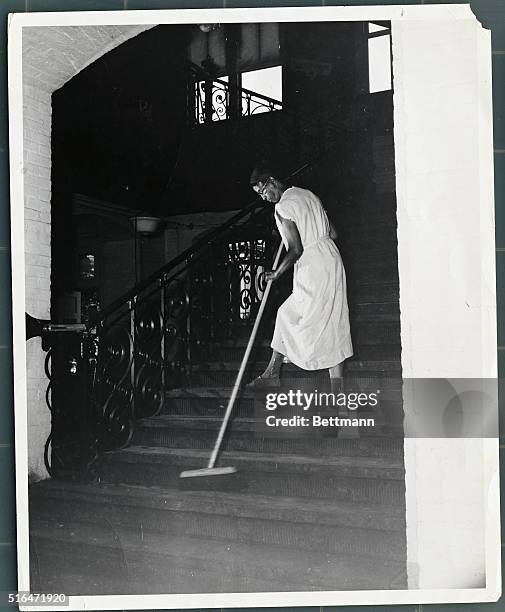 Government cleaning woman Ella Watson brooming down departmental stairs. Undated photograph.