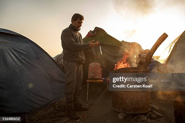 Man warms his hands by a fire at the Idomeni refugee camp on the Greek Macedonia border on March 19, 2016 in Idomeni, Greece. Thousands of migrants...