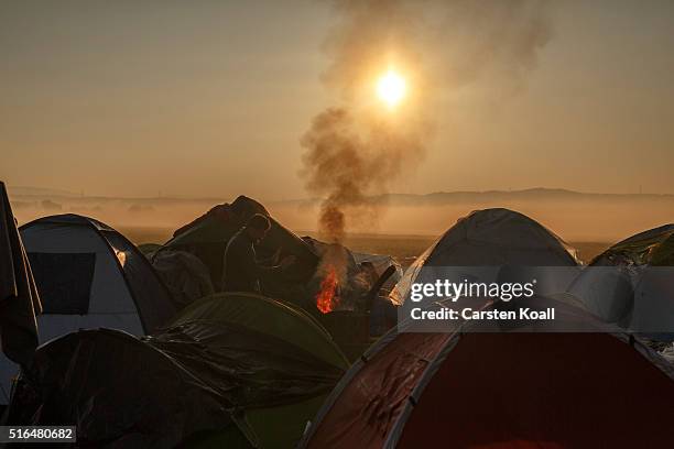 Man warms his hands by a fire at the Idomeni refugee camp on the Greek Macedonia border on March 19, 2016 in Idomeni, Greece. Thousands of migrants...