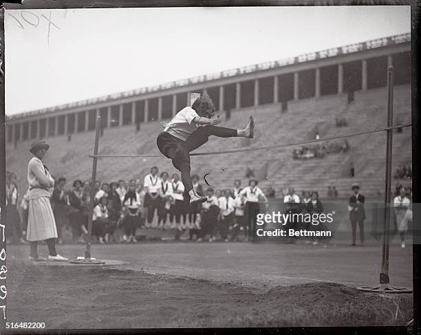 Girl Athletes in Track Meet at Harvard. Cambridge, Massachusetts: Miss M. Jones of the Holyoke Y.M.C.A. Clearing the bar at 4 feet 6 inches, breaking...