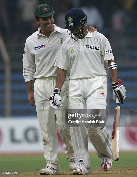 Justin Langer of Australia leaves the field with Sachin Tendulkar of India as play is abandonned because of bad light despite the use of the grounds...