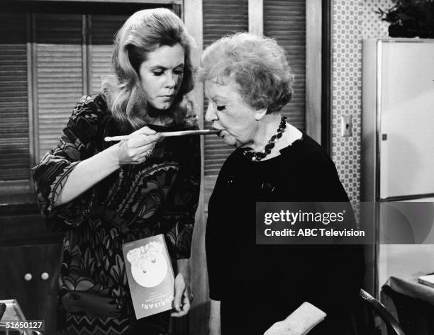 American actress Elizabeth Montgomery feeds American actress Marion Lorne with a wooden cooking spoon as she holds a cookbook entitled 'Sukiyaki: the...