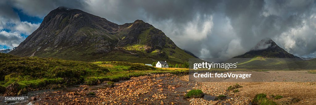 Mountain cottage below dramatic wilderness peaks panorama Glencoe Highlands Scotland