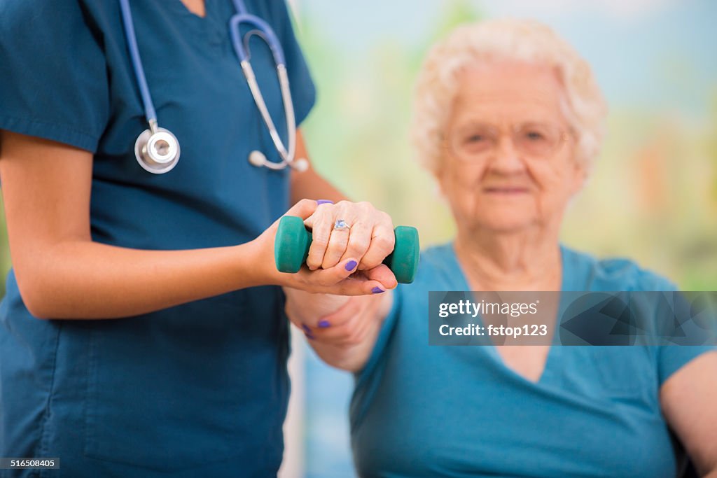 Nurse does physical therapy with senior woman patient. Arm strengthening.