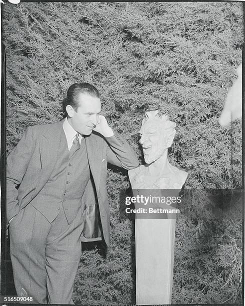 Envy?...Harold Lloyd, popular movie comedian, inspects a laughing statue in the gardens of the home of Lilyan Tashman and Edmund Lowe, during the...