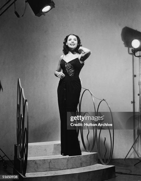 American blues singer and actress Lena Horne sings on a stage set of stairs and wears a floor length gown, 1940s.