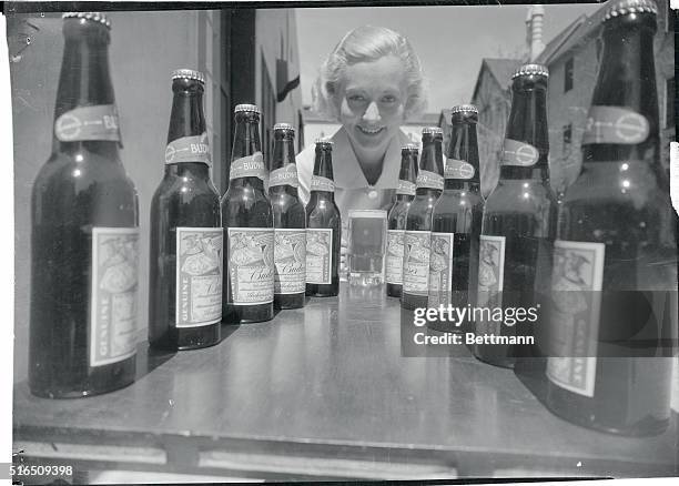 Big bottles of thirst-quenching beer line the way down to Shirley Grey, movie actress, as she prepares to quaff a stein of the foaming brew on the...