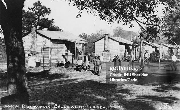 Landscape of the African American quarters on the Lewis Plantation in Brooksville, Florida, young African American men walking on the grass in front...