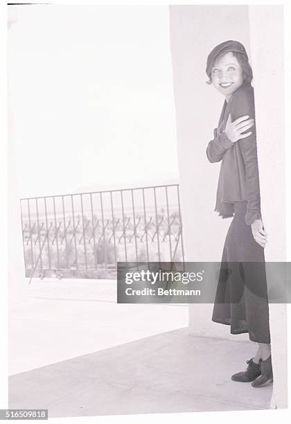 Lofty mountains loom above the barren desert as Nancy Carroll, motion picture star, views the arid surroundings from her lofty perch in the tower of...