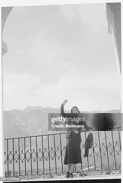 Lofty mountains loom above the barren desert as Nancy Carroll, motion picture star, views the arid surroundings from her lofty perch in the tower of...