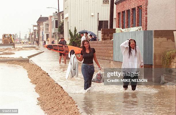 Rain-soaked residents of Seal Beach wade through ankle deep water along the flooded boardwalk of this Orange County beach community after heavy rains...