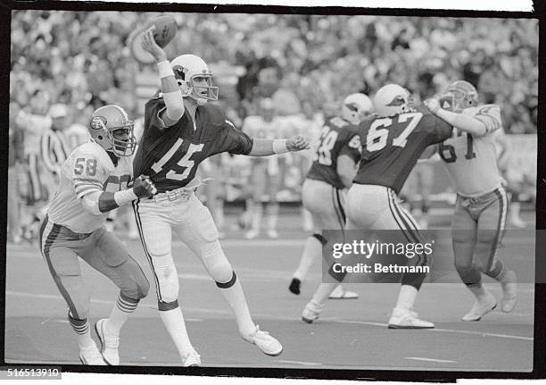 San Francisco 49er grabs St. Louis Cardinals' quarterback Neil Lomax from behind but he is still able to flip a short pass to Stump Mitchell in the...