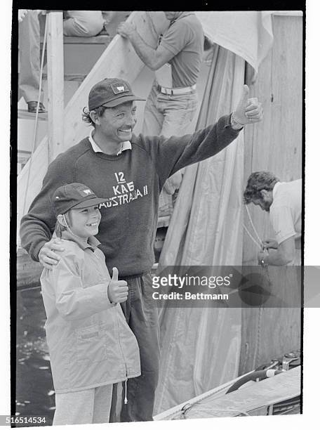 Newport, R.I.: Australia II skipper John Betrand and son Lucas "thumbs-up" dockside after the victorious crew defeated the American 12-meter yacht...